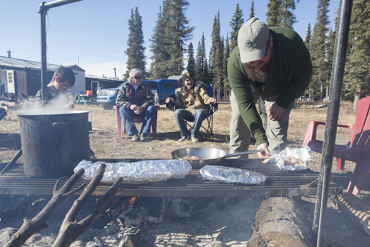 Tom Buzzell keeps an eye on a feast of moose meat, salmon and beaver tail.