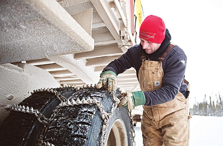 Malcolm MacPhail chains up outside Wrigley. The fines for not equipping a transport truck with wheels change from week to week, but they're always hefty. Photo by Angela Gzowski