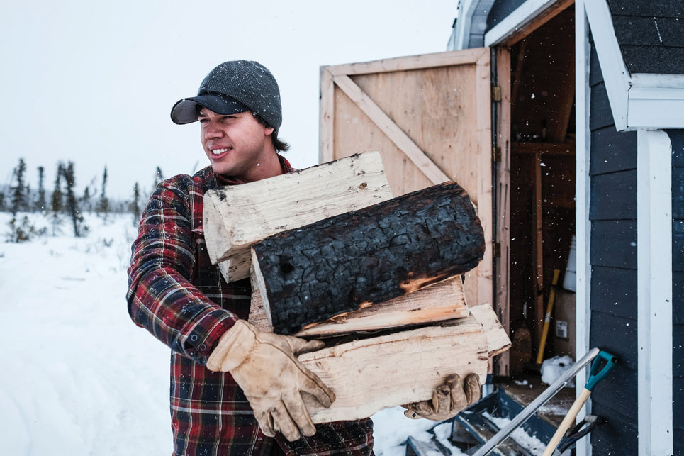 Matt Lavoie stocks his woodpile at his Airport Lake cabin. Photo by Weronika Murray