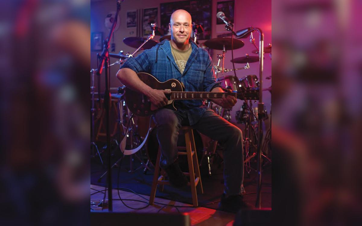 Travis Pryor posing with his guitar.