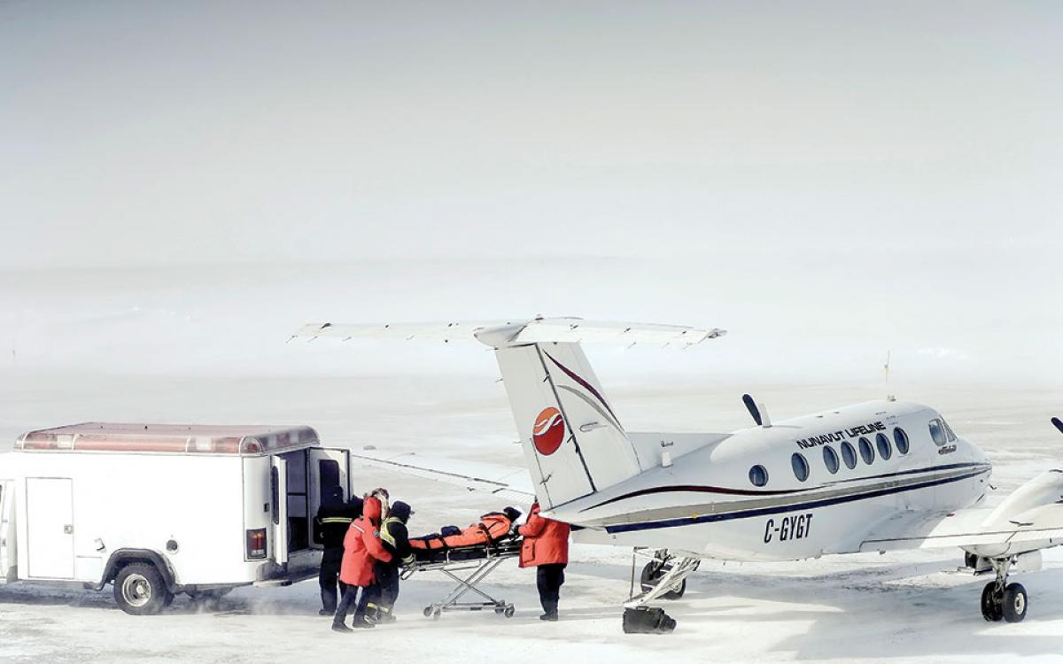 Nunavut Lifeline: Medics rush a patient in Arviat onto a King Air 200 for a medevac to Manitoba before a winter storm hits. Photo by Paul Aningat. 
