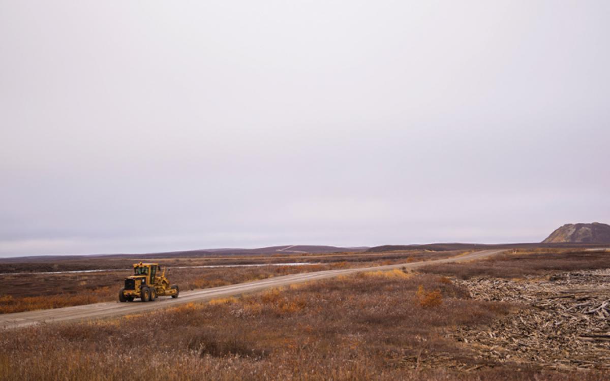 Pingos dot the landscape along the road winding south out of Tuktoyaktuk. Ryan Yakeleya, an E. Gruben's employee, drives a grader toward the Tuk-Inuvik highway worksite. Photo by Angela Gzowski