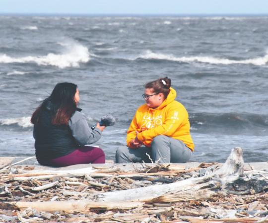 Mataya Gillis and Cassidy Lennie-Ipana talking on the shore. 