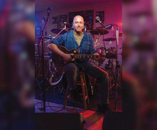 Travis Pryor posing with his guitar.