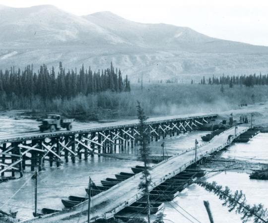 Permanent wood piles replace a temporary pontoon bridge on the Alaska Highway. Photo courtesy of Yukon Archives, R.A. Cartter fonds #1498